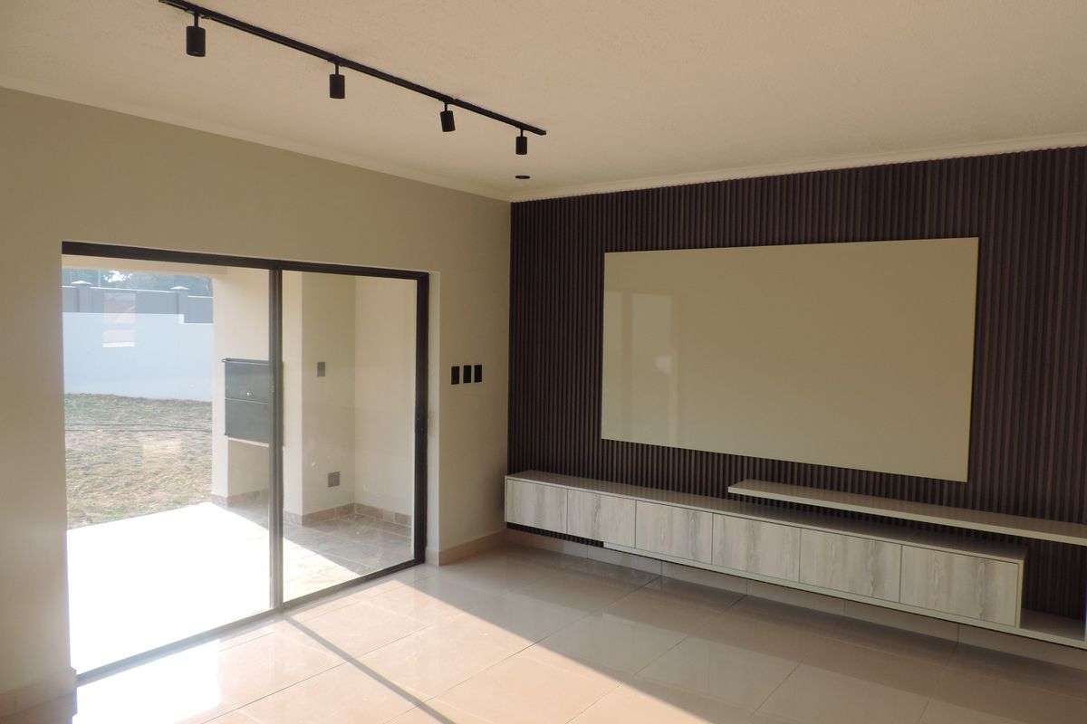 Modern living room featuring a slatted wood accent wall, built-in floating cabinetry, track lighting, and large sliding glass doors opening to an outdoor patio area.