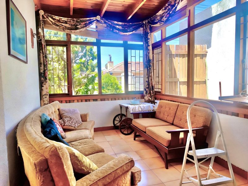 A sun-drenched enclosed patio featuring a timber ceiling, tiled flooring, and large windows that provide ample natural light and garden views.
