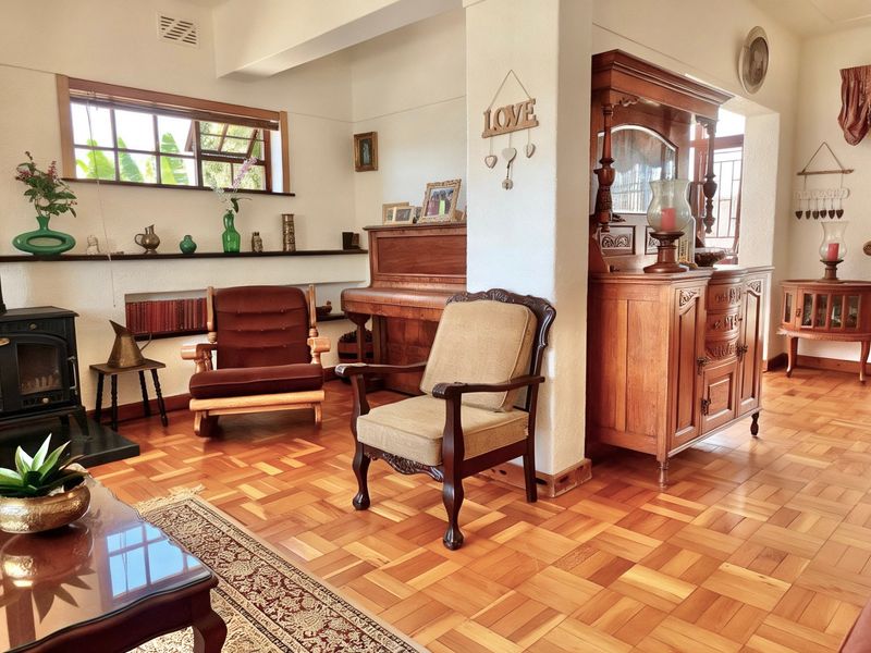 A cozy living room featuring warm parquet flooring, a cast iron fireplace, and built-in shelving, offering a classic and inviting atmosphere.