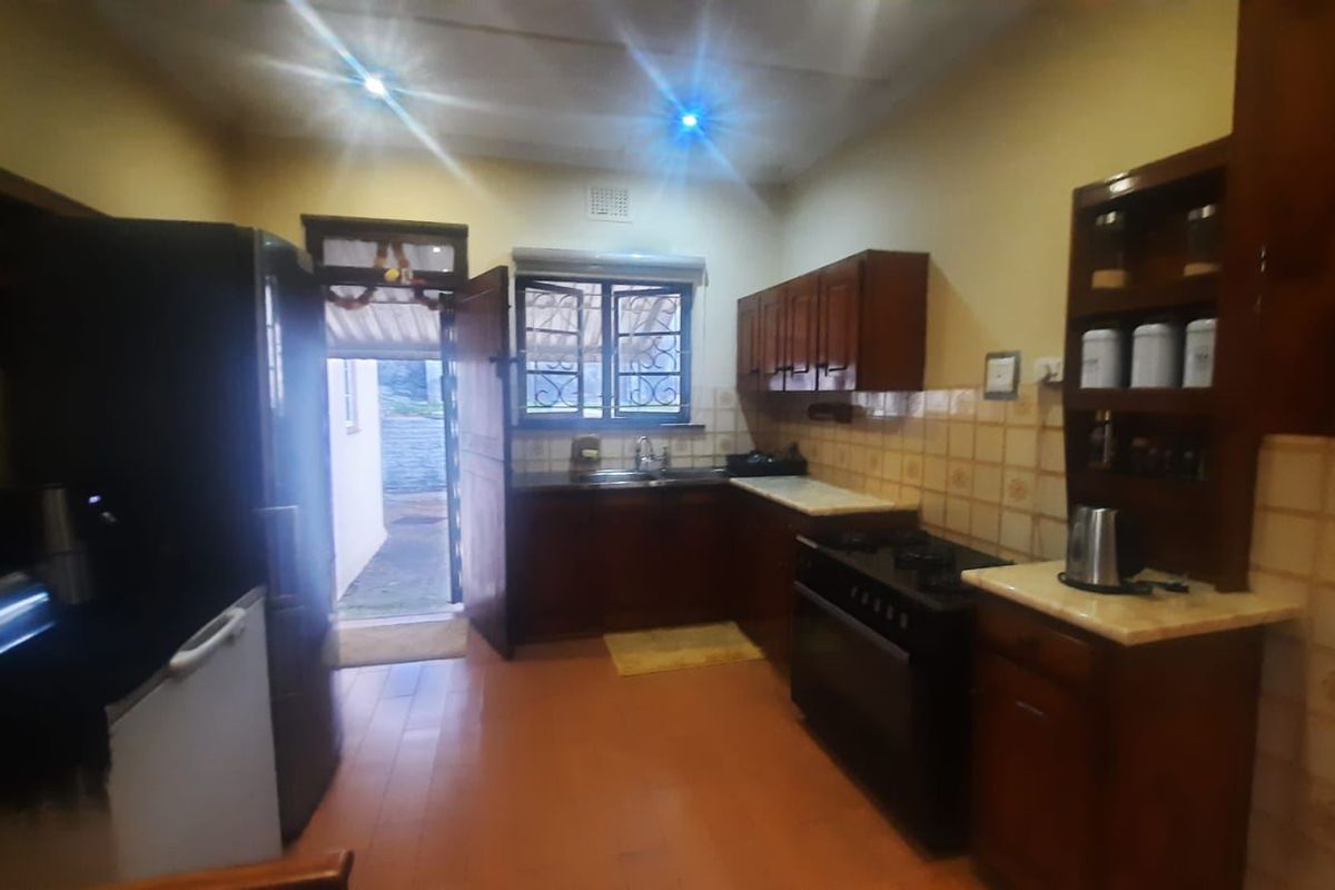 A functional kitchen featuring wooden cabinetry, tiled backsplash, built-in stove and oven, and direct access to the exterior.
