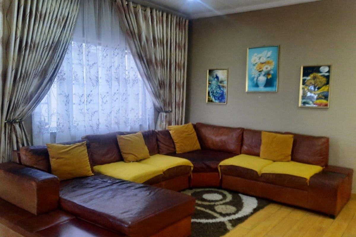 A comfortable living room featuring laminate flooring and large window treatments, providing a functional and inviting space for relaxation.