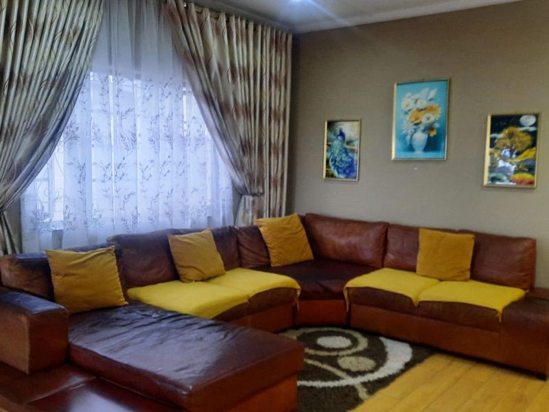A comfortable living room featuring laminate flooring and large window treatments, providing a functional and inviting space for relaxation.