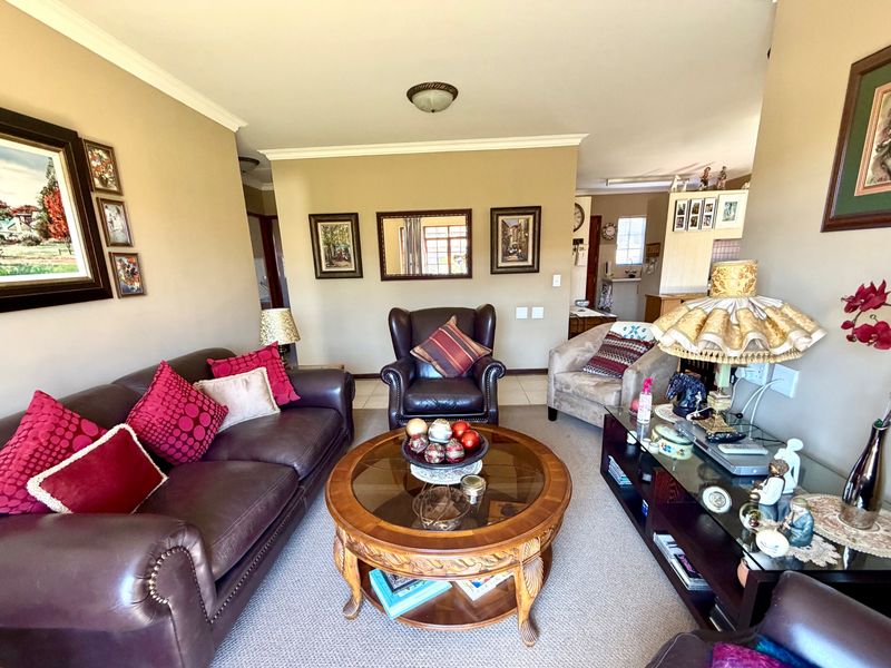 A comfortable living room featuring neutral wall tones, crown molding, and tiled flooring, providing a functional space for relaxation.