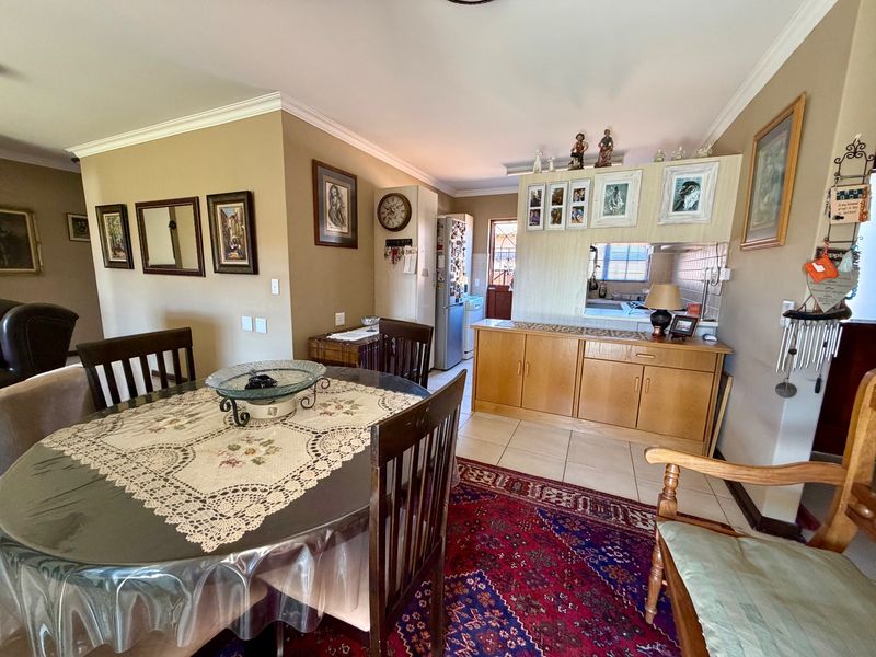 Open-plan dining area featuring tiled flooring, coved cornicing, and a built-in kitchen pass-through with cabinetry, connecting to the adjacent kitchen space.