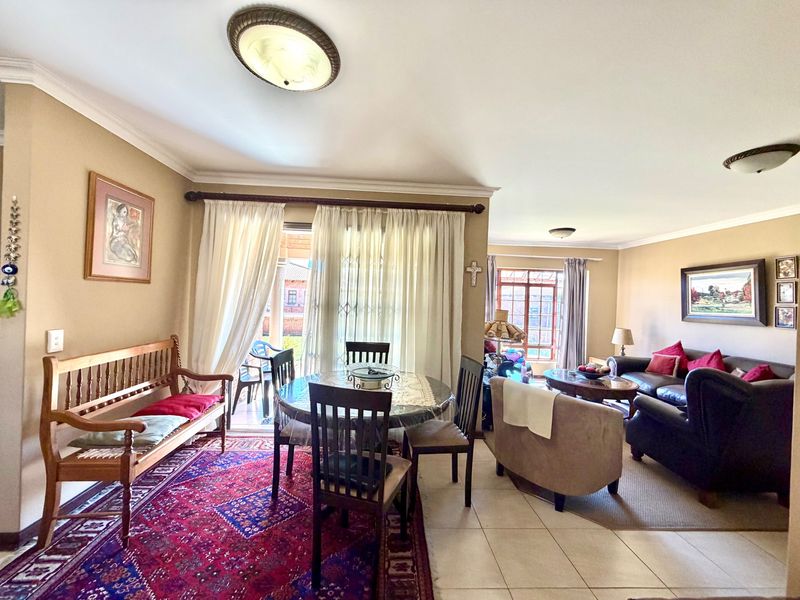 Spacious open-plan living and dining area featuring tiled flooring, neutral walls, and direct access to an outdoor patio through sliding glass doors.