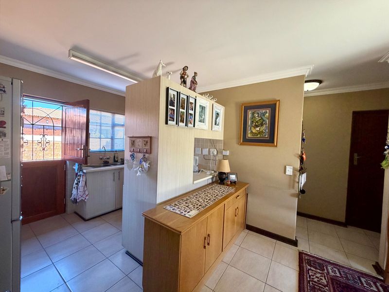 A functional kitchen area featuring tiled flooring, built-in cabinetry, and a partition wall, with direct access to an exterior security gate.