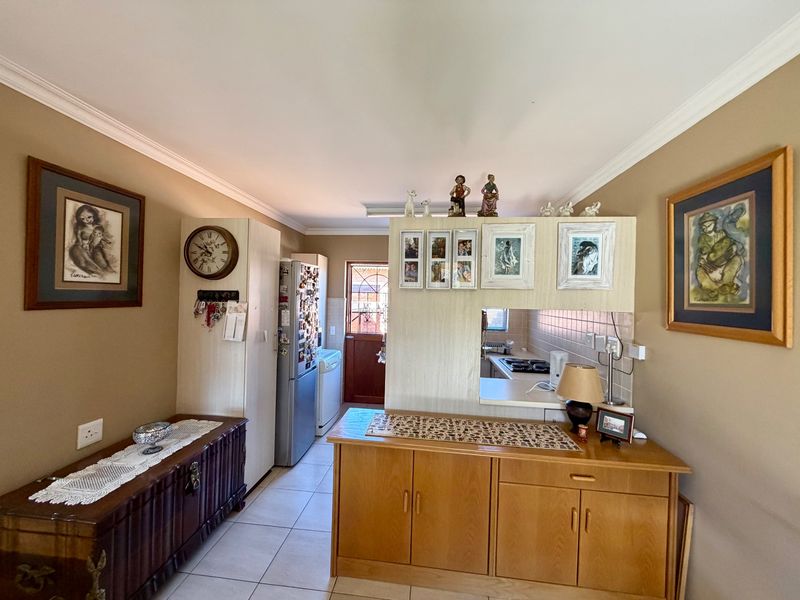 Open plan kitchen and living area featuring tiled flooring, built-in cabinetry, and a functional pass-through window connecting the kitchen to the living space.