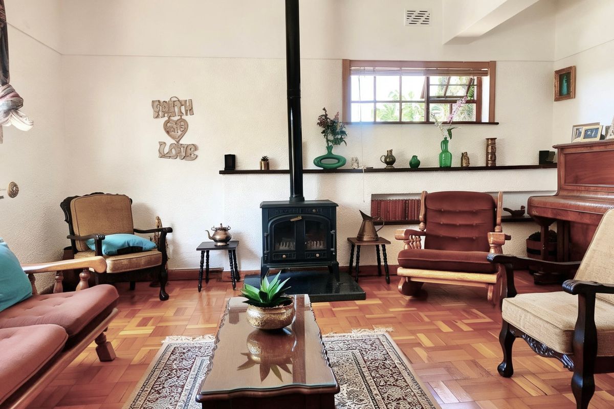 A cozy living room featuring classic parquet flooring, a prominent freestanding wood-burning fireplace, and built-in wall shelving under a timber-framed window.