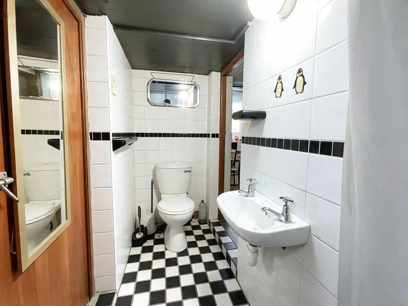 A compact bathroom featuring a wall-mounted basin, toilet, and classic black and white tiled finishes.