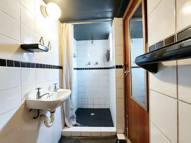 A functional bathroom featuring a wall-mounted basin and a walk-in shower with tiled finishes.