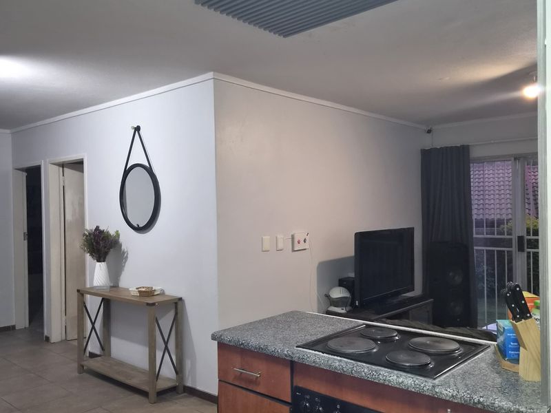 Open plan kitchen and living area featuring tiled floors, granite countertops, and a built-in oven with electric hob, leading to a sliding door.
