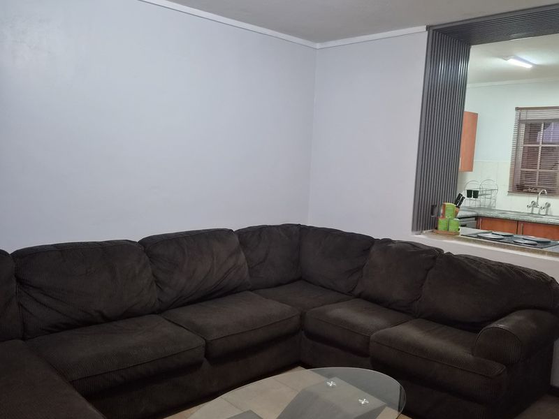 Open plan living area featuring tiled flooring and a convenient pass-through window connecting to the kitchen space.