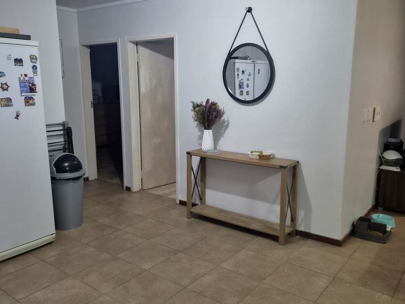 A living area featuring neutral tiled flooring and standard ceiling lighting, providing a functional space with potential for cosmetic updates.