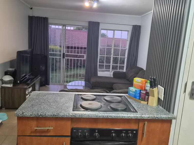 Open-plan living area featuring a kitchen island with built-in oven and hob, flowing into a lounge space with access to the rear garden.