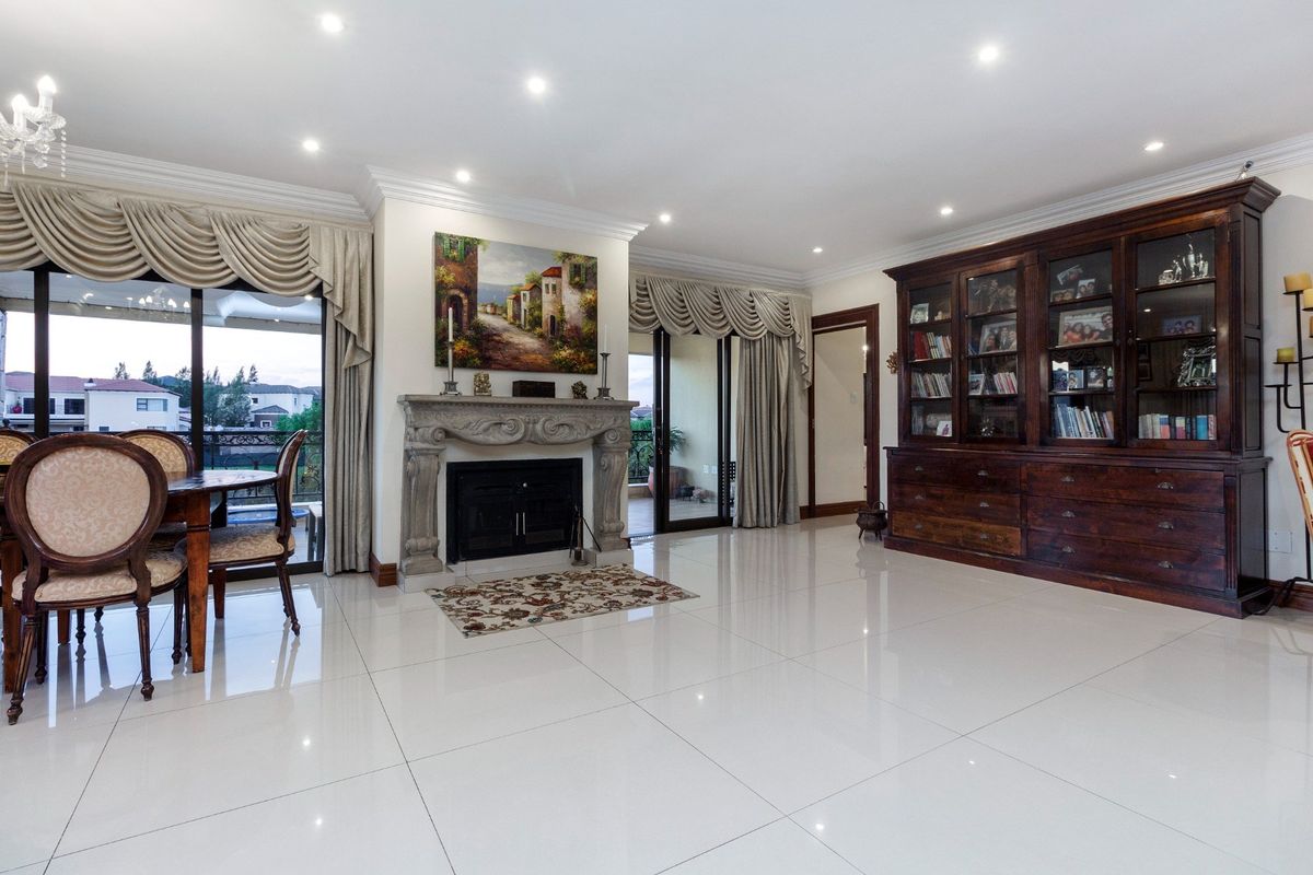 Spacious living area featuring polished tile floors, a decorative stone fireplace, built-in cabinetry, and large sliding doors leading to an outdoor balcony.