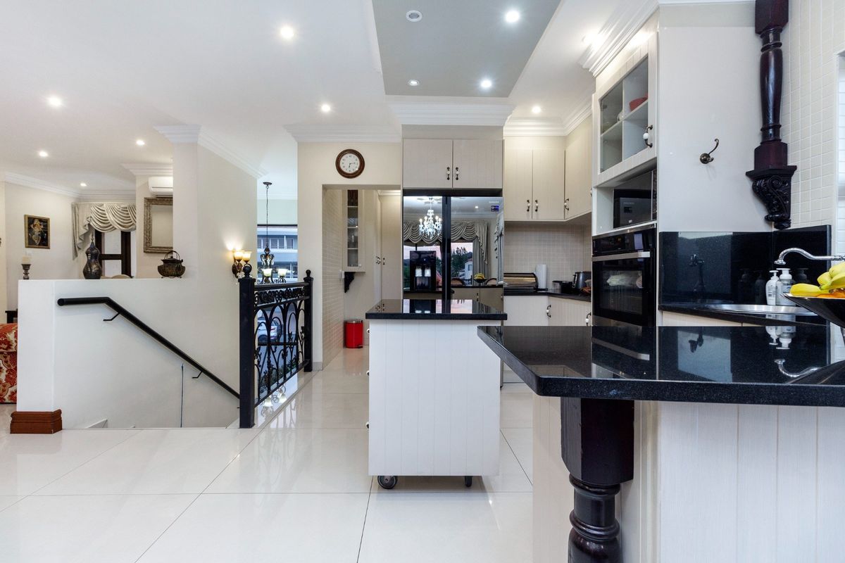 Modern kitchen featuring sleek granite countertops, ample built-in cabinetry, recessed lighting, and polished tile flooring, seamlessly integrated with the home's open-plan layout.