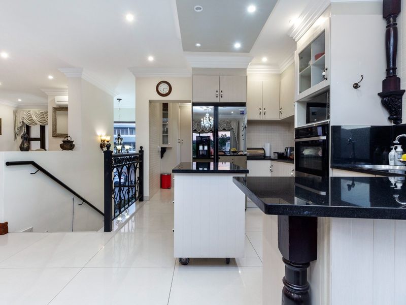 Modern kitchen featuring sleek granite countertops, ample built-in cabinetry, recessed lighting, and polished tile flooring, seamlessly integrated with the home's open-plan layout.