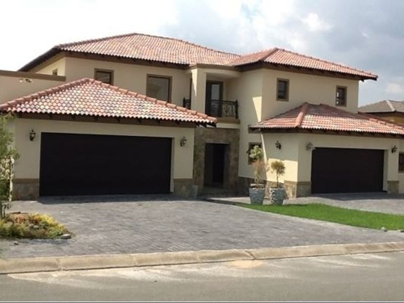 A well-maintained double-story residential property featuring a tiled roof, stone accents, a paved driveway, and a double garage.