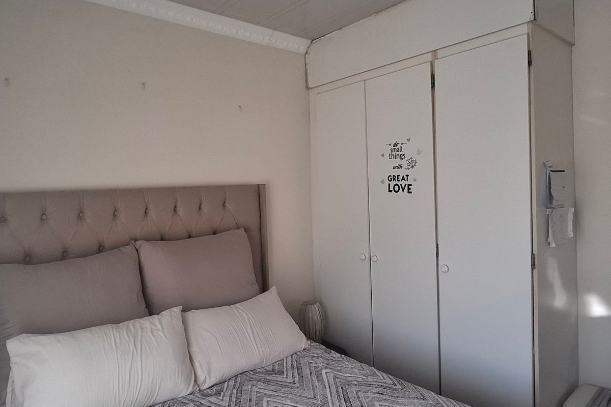 A bedroom featuring built-in cupboards with overhead storage and decorative ceiling cornice, providing functional storage space within the room.