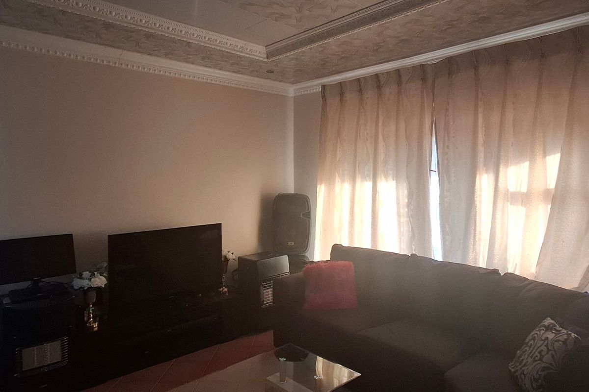 A living room featuring decorative ceiling molding and tiled flooring, providing a comfortable space for relaxation.
