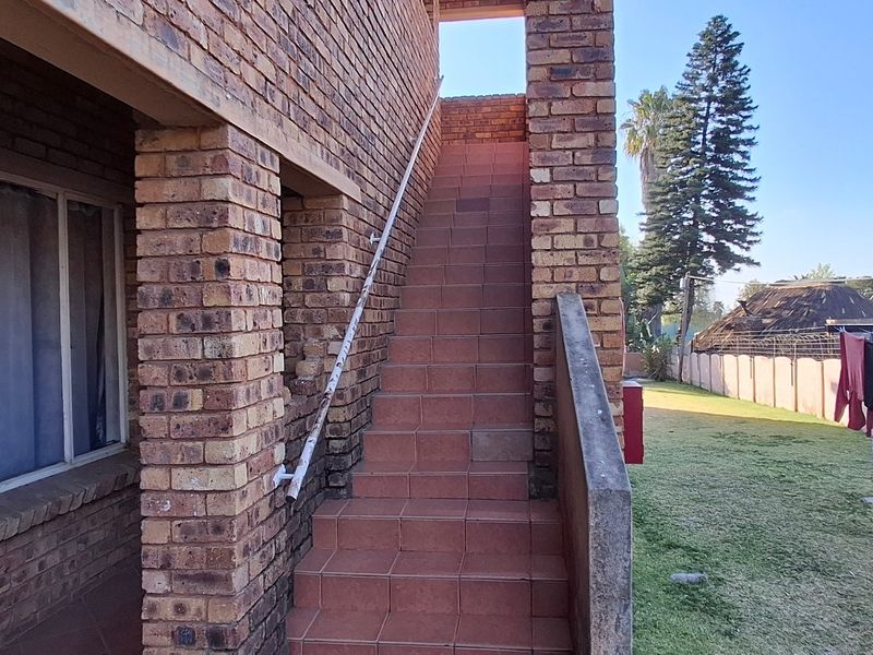 Exterior view of a townhouse featuring a face brick facade and an external tiled staircase leading to an upper level.