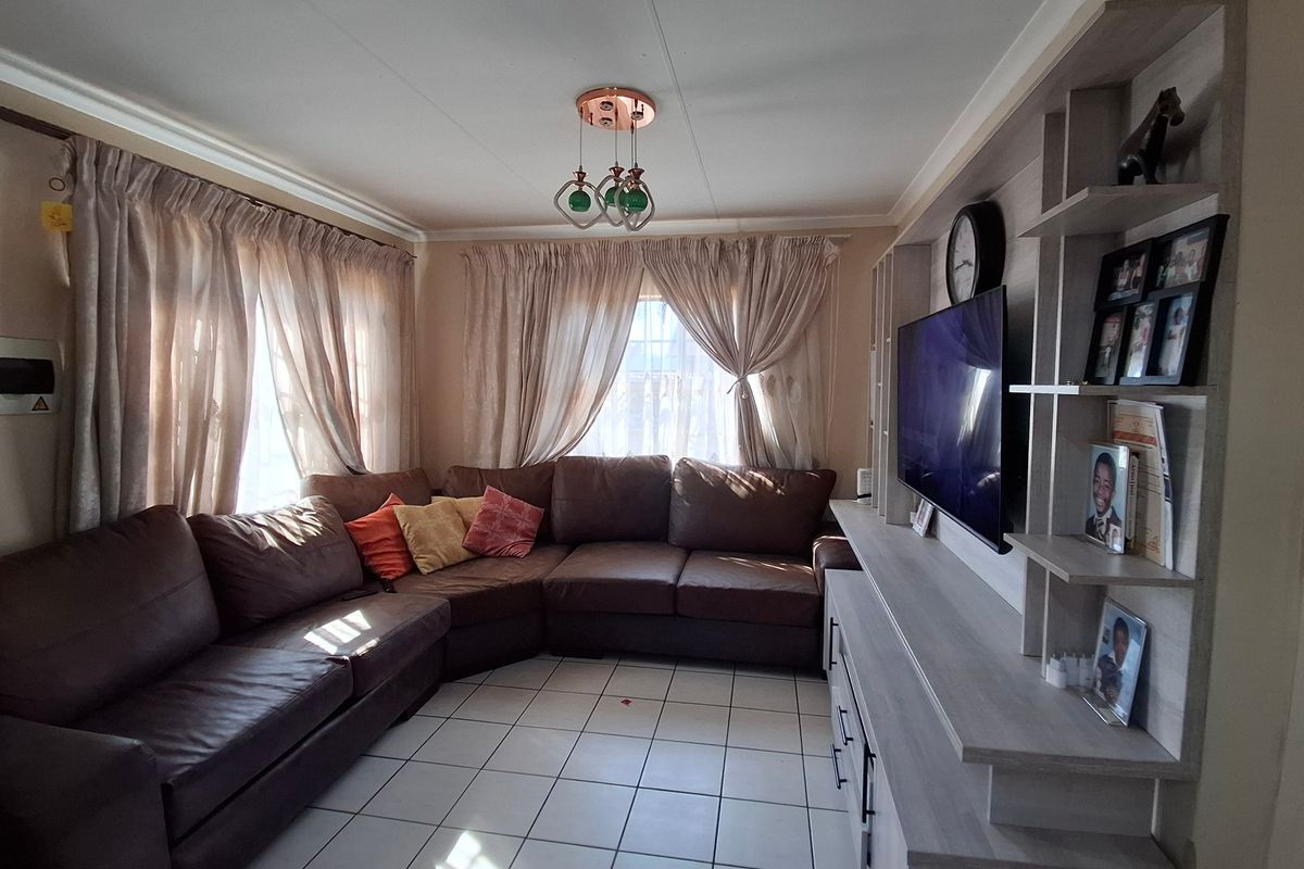 A comfortable living room featuring tiled flooring and a large built-in shelving unit, providing ample storage and display space.