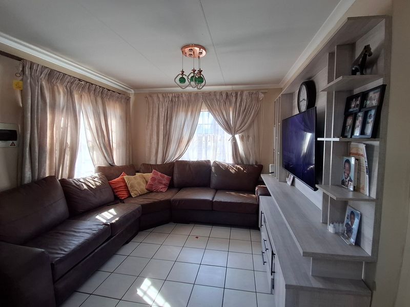 A comfortable living room featuring tiled flooring and a large built-in shelving unit, providing ample storage and display space.