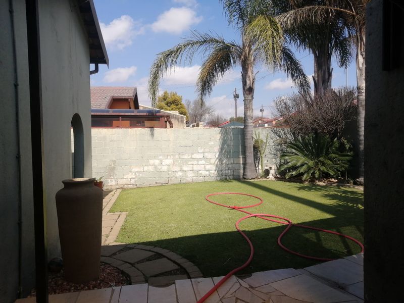 A private rear garden featuring a paved patio area, artificial lawn, and a perimeter boundary wall.