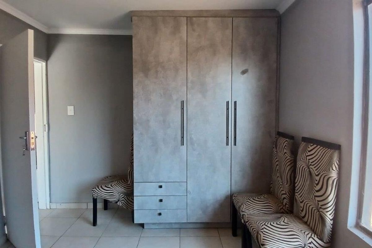 Bedroom featuring a modern built-in wardrobe with a textured finish and neutral tiled flooring.