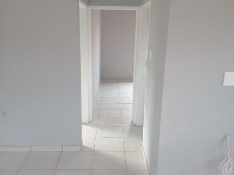 A clean, empty hallway featuring neutral grey walls, white ceramic floor tiles, and classic coving detail.