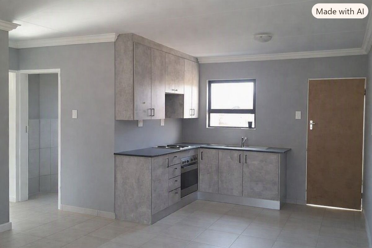 A clean, modern kitchen featuring grey cabinetry, built-in oven and hob, stainless steel sink, and neutral tiled flooring.