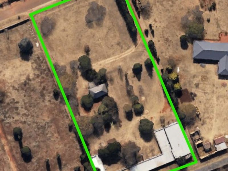 Aerial view of the farm property showing the land boundaries, existing structures, driveway access, and established trees on the plot.
