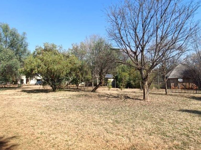 A spacious, open garden area on the farm property featuring mature trees and perimeter fencing.