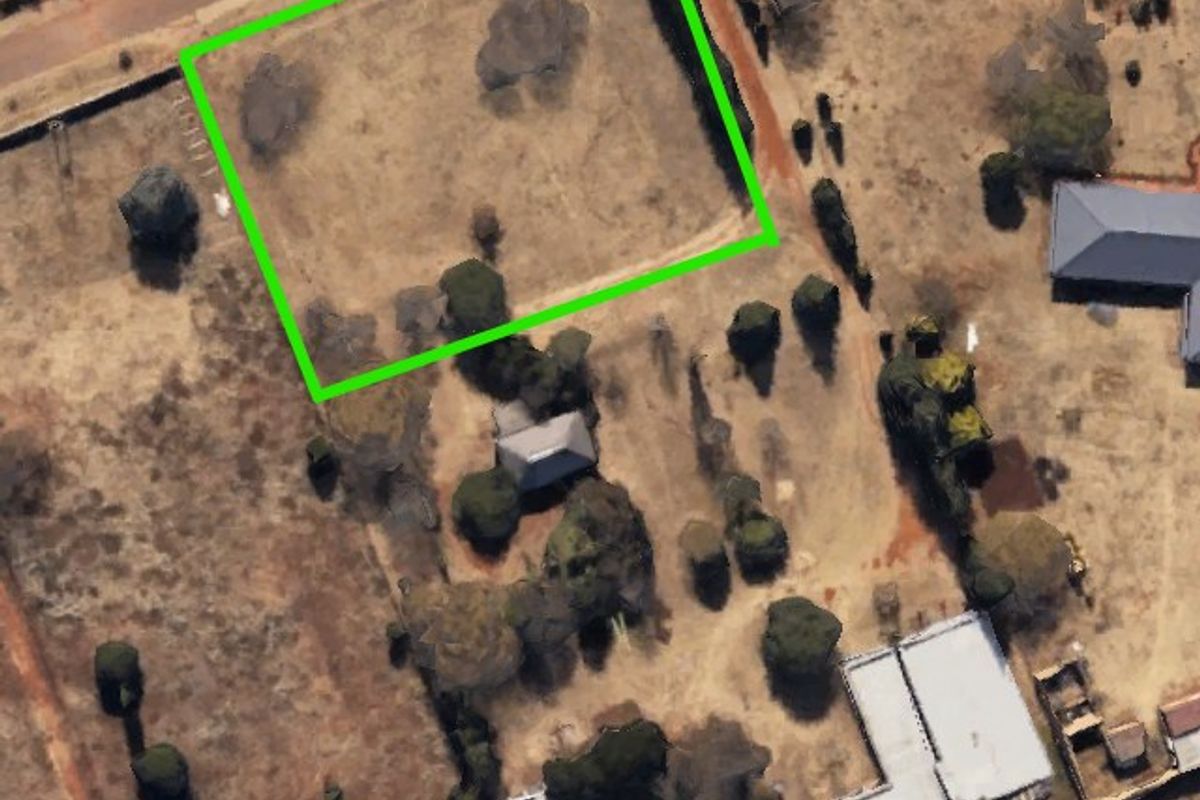 Aerial view of a large, undeveloped farm plot with a highlighted boundary, featuring mature trees and open land.