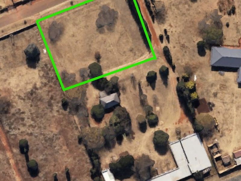 Aerial view of a large, undeveloped farm plot with a highlighted boundary, featuring mature trees and open land.
