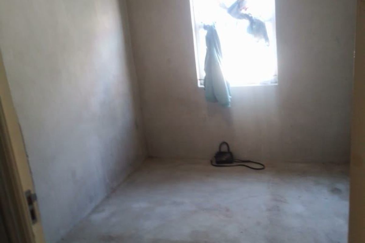 An empty bedroom featuring unfinished plaster walls and flooring, offering a blank canvas for renovation and custom interior finishes.