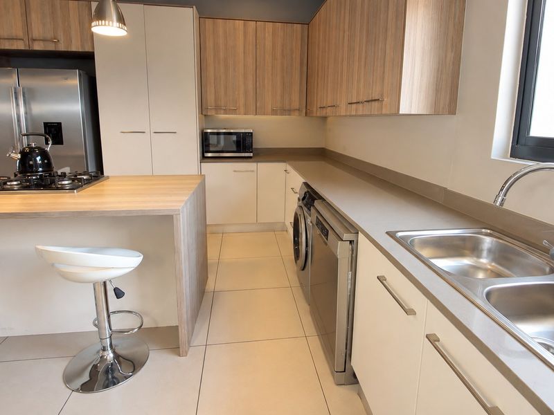 Modern kitchen featuring light wood and white cabinetry, stone countertops, a gas hob on the island, and integrated appliances.