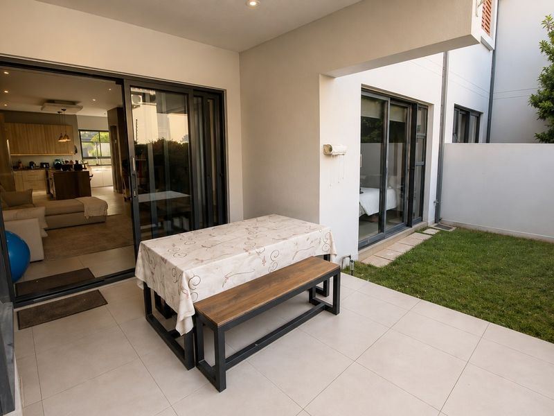 A covered patio area featuring tiled flooring and sliding glass doors that provide seamless access to the interior living space and adjacent garden.