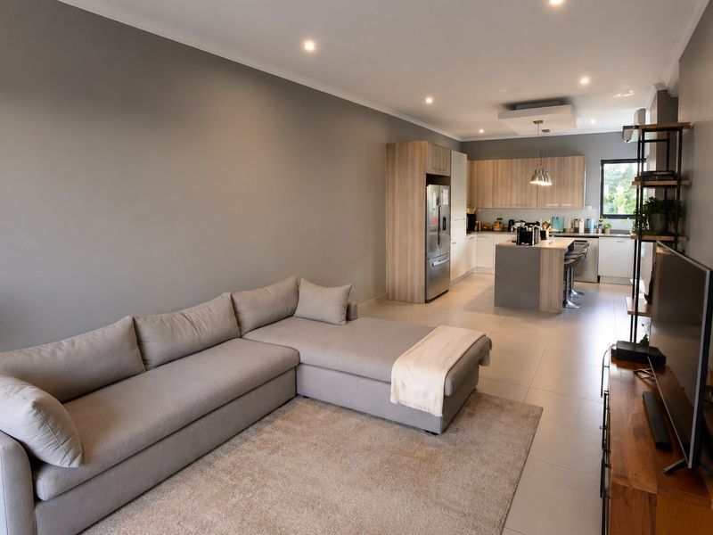 Modern open-plan living area featuring a contemporary kitchen with a central island, sleek cabinetry, and neutral tiled flooring throughout.