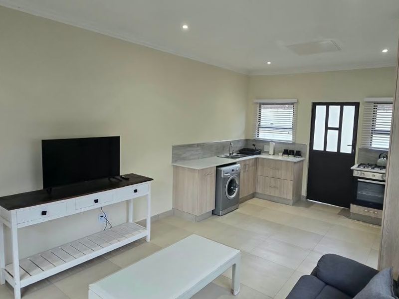 Open-plan living area featuring a modern kitchen with built-in cabinetry, oven, hob, and tiled flooring, seamlessly connecting to the living space.
