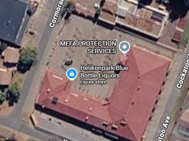 Aerial view of a commercial property featuring a central parking area and a large building with a pitched roof.