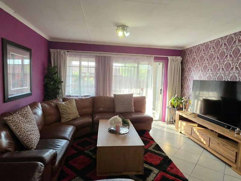A comfortable living room featuring tiled flooring, a sliding glass door providing natural light, and a distinct accent wall.