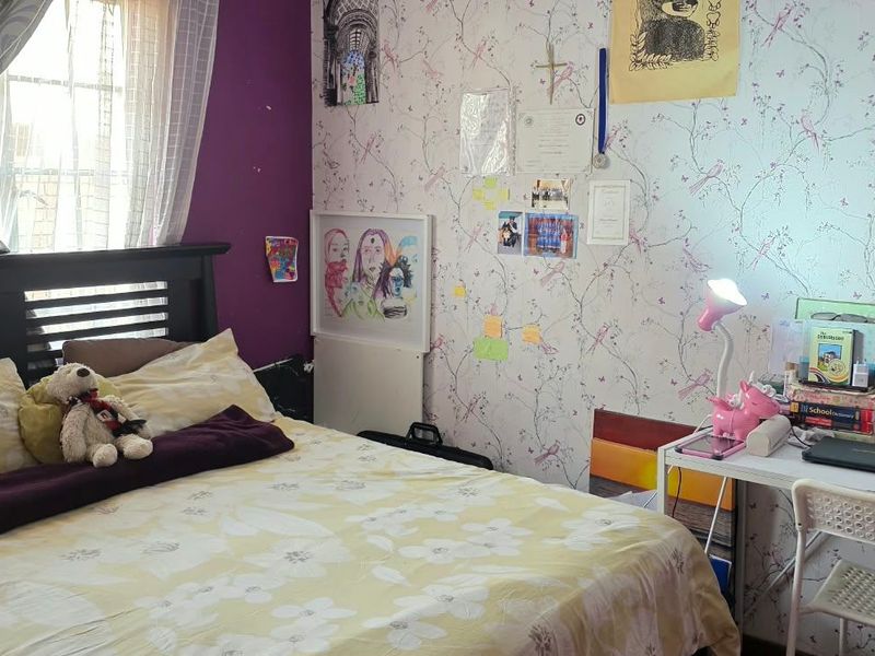 A bedroom featuring a window with curtain rails and patterned wallpaper.