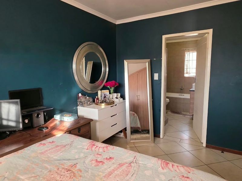 A bedroom featuring dark painted walls, tiled flooring, and direct access to an adjoining bathroom.