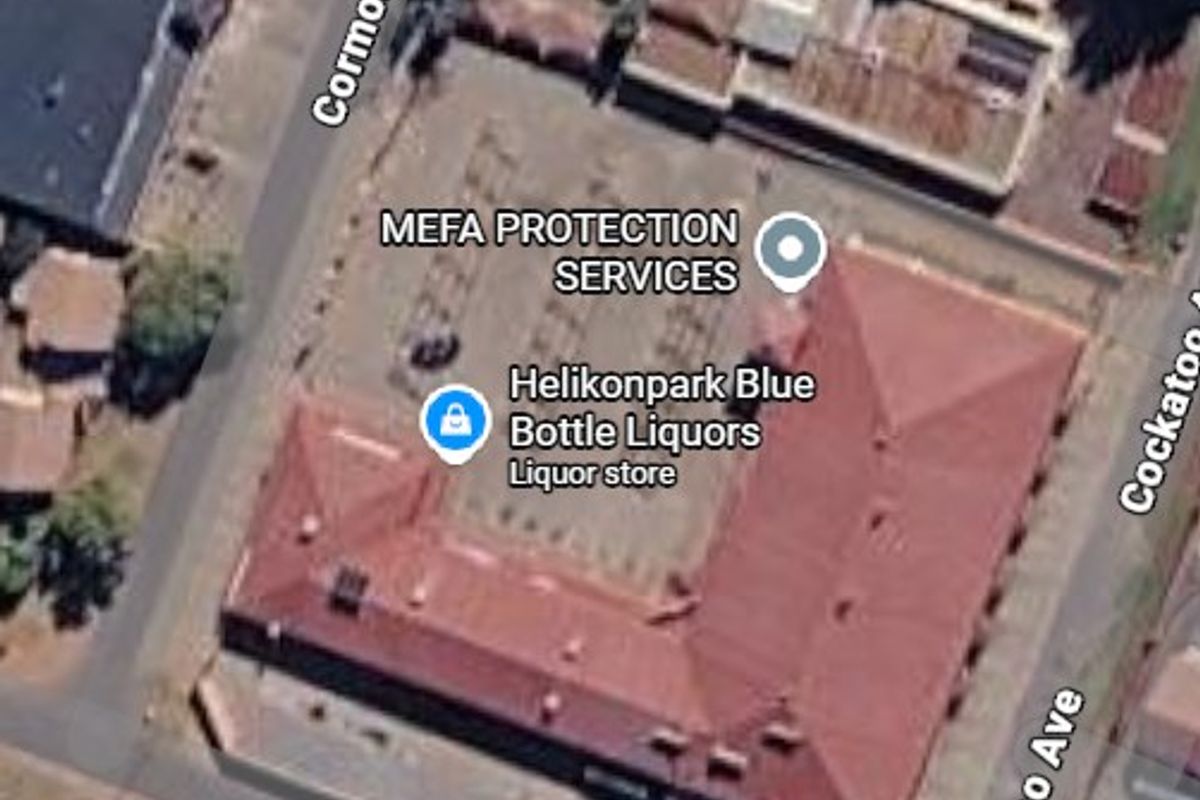 Aerial view of a commercial property featuring a central parking area and a large building with a pitched roof.