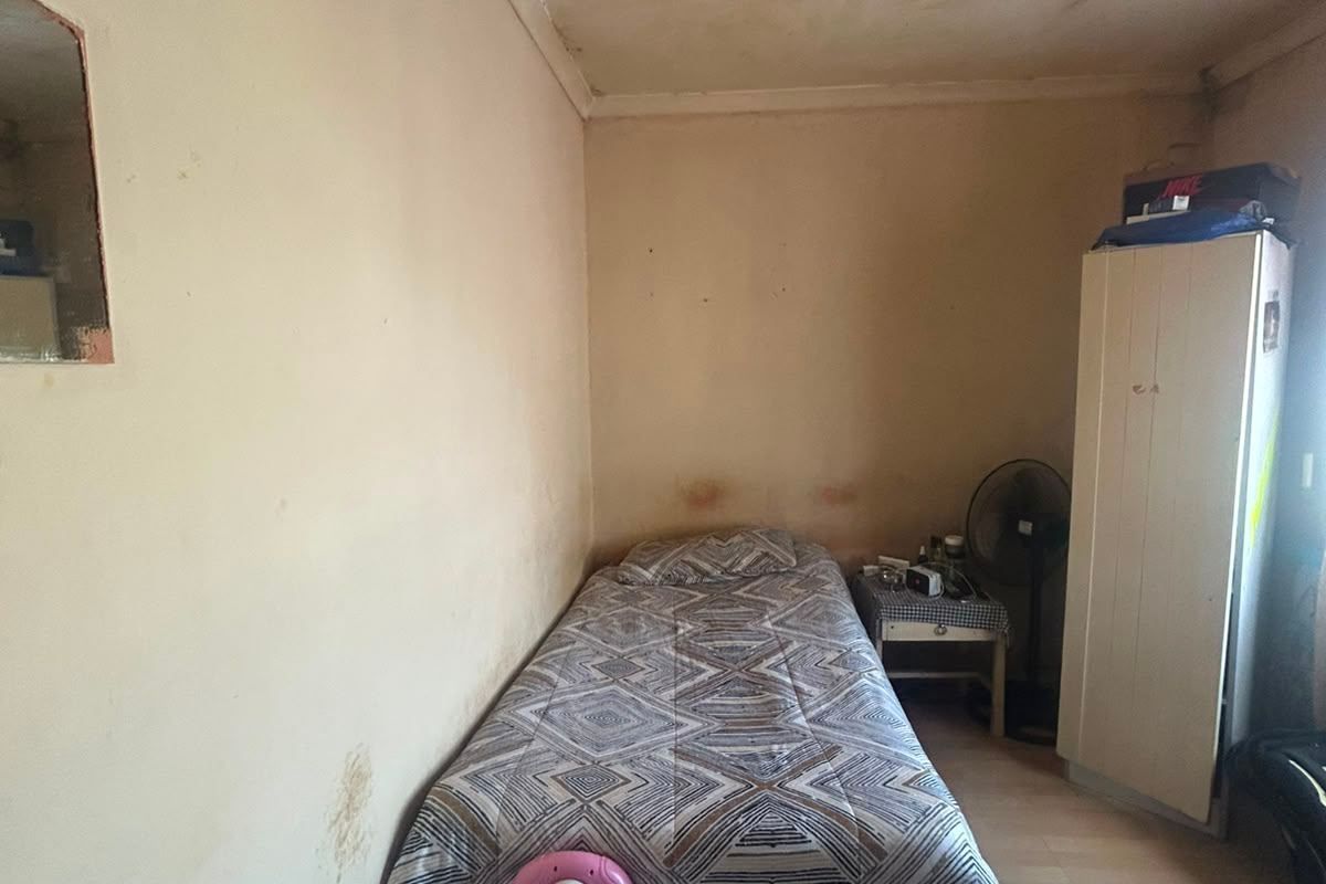 A bedroom space requiring significant maintenance, featuring visible ceiling and wall damage that needs repair and refurbishment.