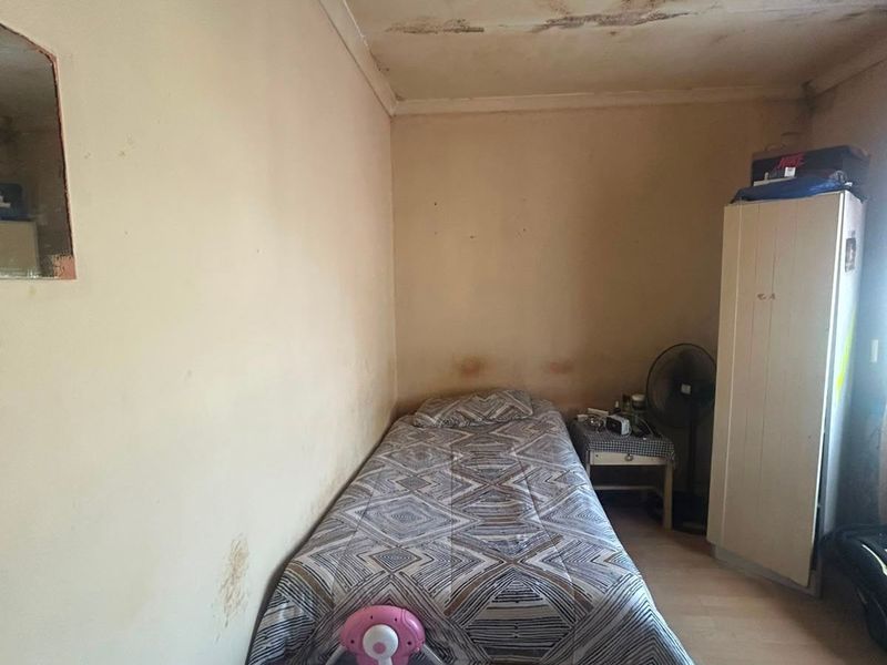 A bedroom space requiring significant maintenance, featuring visible ceiling and wall damage that needs repair and refurbishment.