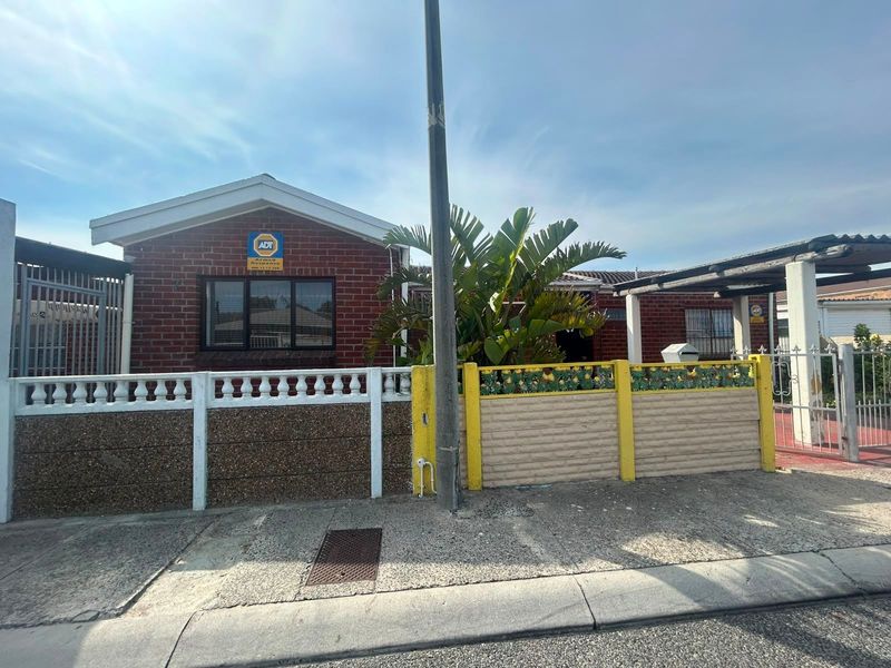 Front view of a brick-faced house featuring a carport, secure boundary walling, and an installed security alarm system.