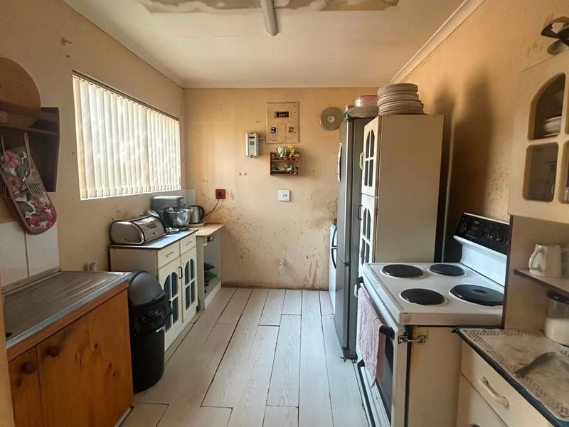 A dated kitchen featuring built-in cabinetry and an electric stove, currently requiring significant cosmetic renovation and repair to the walls and ceiling.