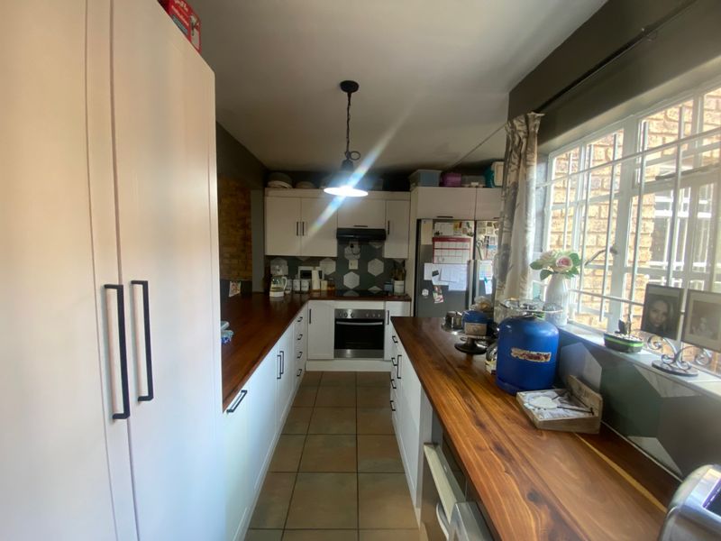 A functional kitchen featuring white cabinetry, warm wooden countertops, a hexagonal tile backsplash, and a built-in oven with an extractor fan.
